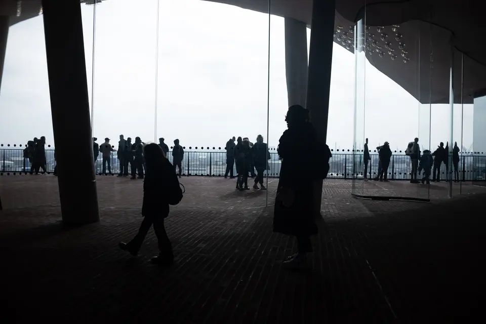 Visitors in silhouette against the bright opening of the Elbphilharmonie plaza