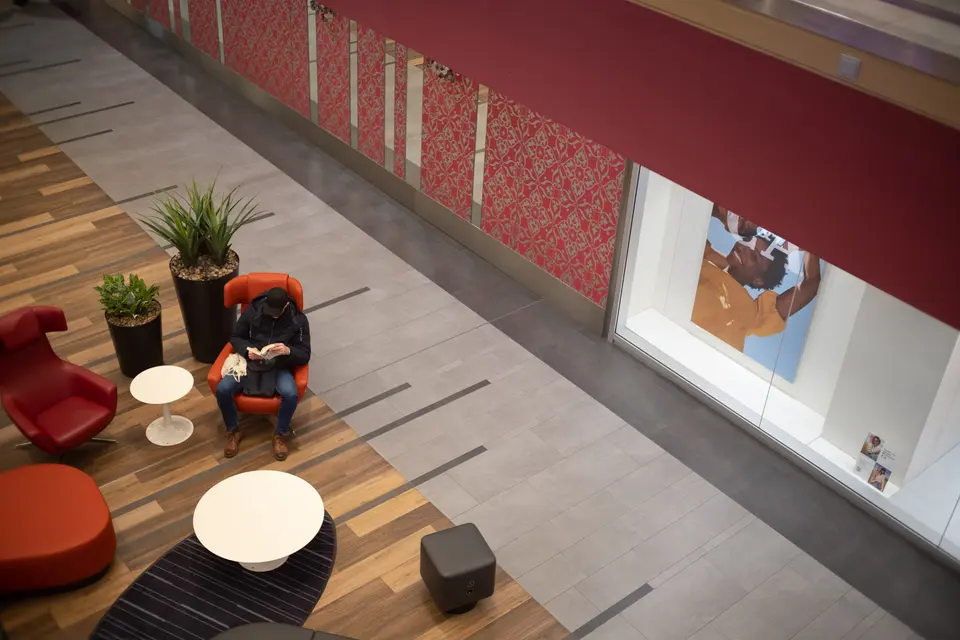A person reading in a red armchair in a lobby, seen from above