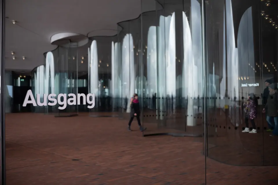 Curved glass walls and an exit sign inside the Elbphilharmonie plaza