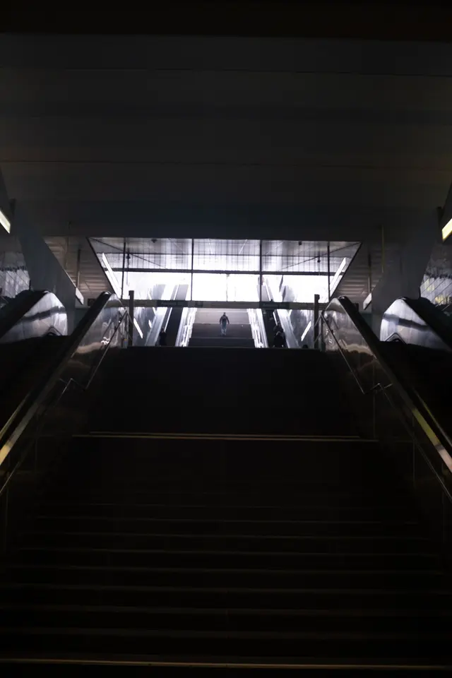 A dark stairway leading up towards daylight under a concrete roof