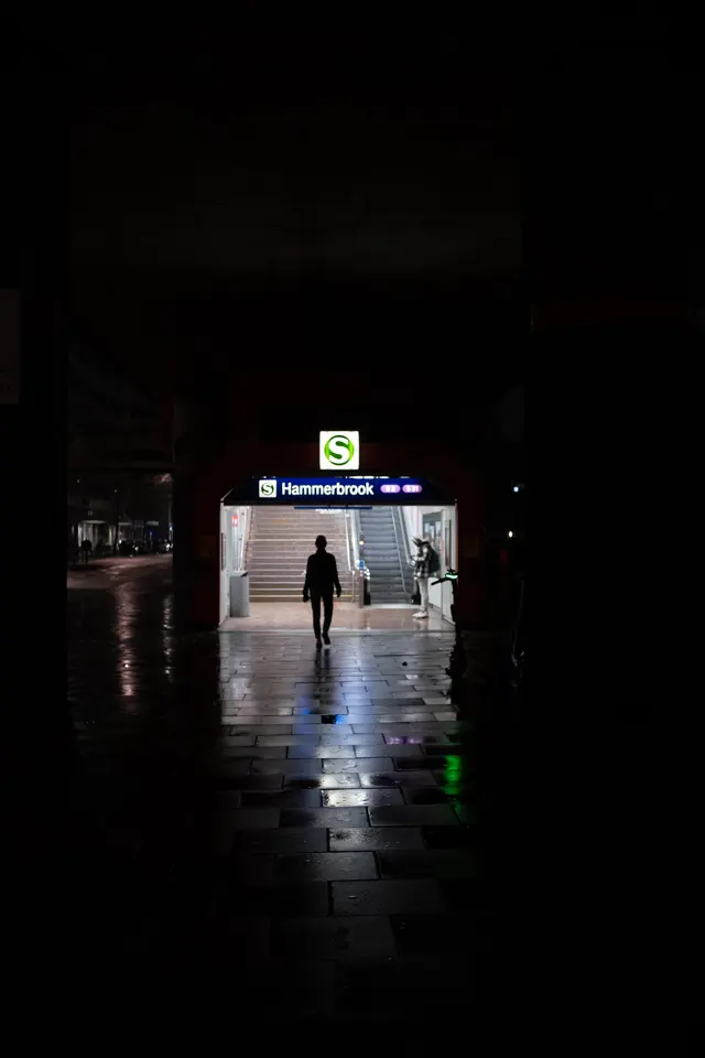 A lone figure walking towards the lit entrance of Hammerbrook station at night