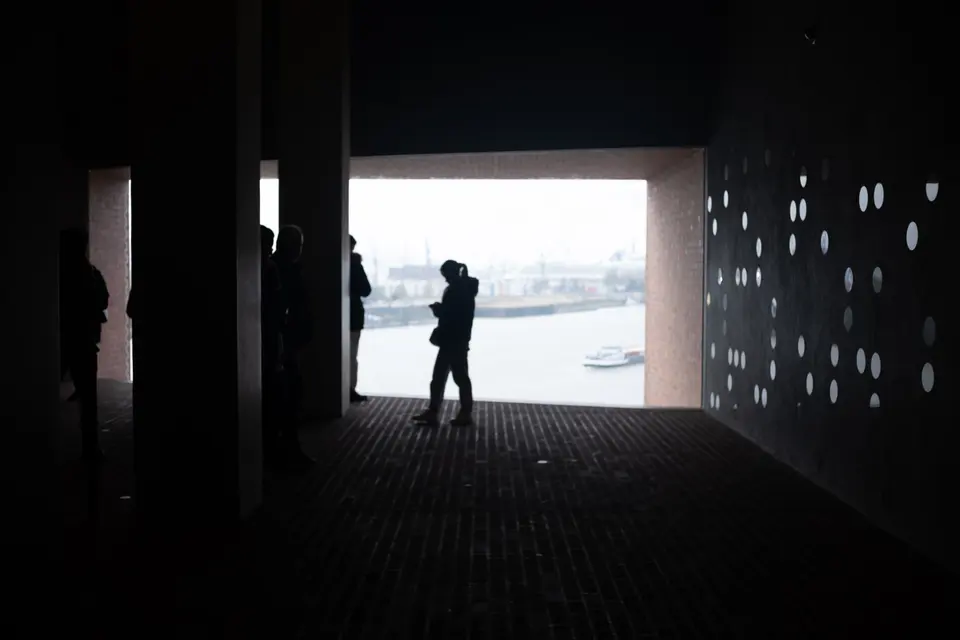 A person in silhouette at the end of a dark passage that opens onto the river