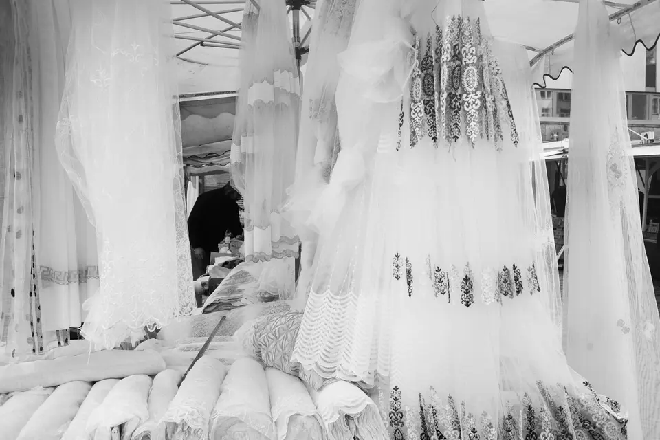 White embroidered dresses hanging at a market stall, in black and white