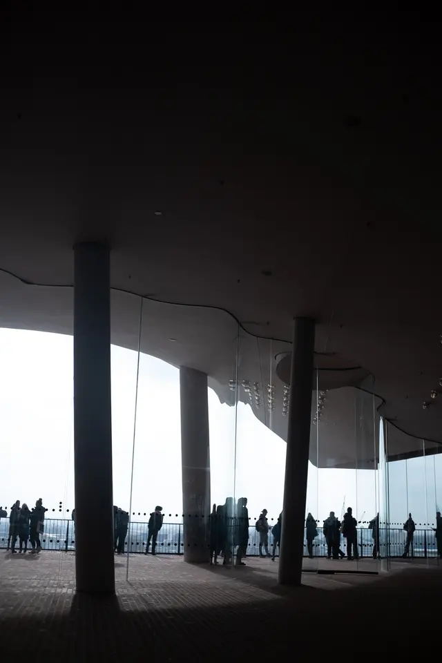 Columns and a curved roof framing the bright plaza opening of the Elbphilharmonie